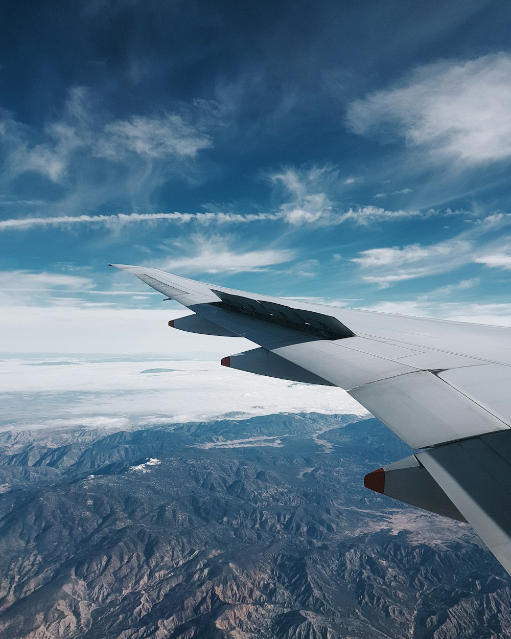 plane flying over grey hills