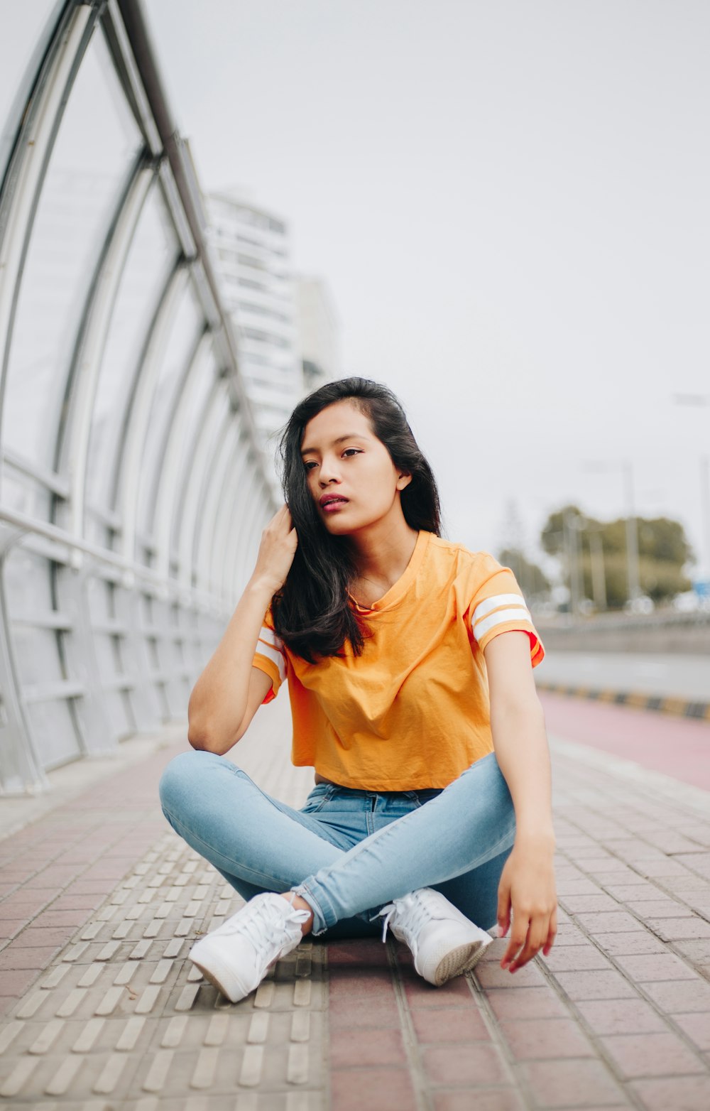 selective focus photography of woman touching hair beside metal rail