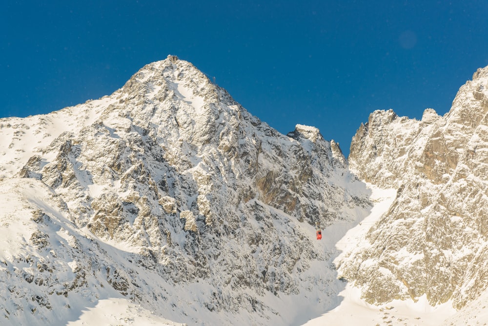 Montaña rocosa cubierta de nieve bajo el cielo azul claro durante el día