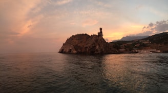 A majestic castle perched on a cliff, bathed in the warm hues of a sunset.