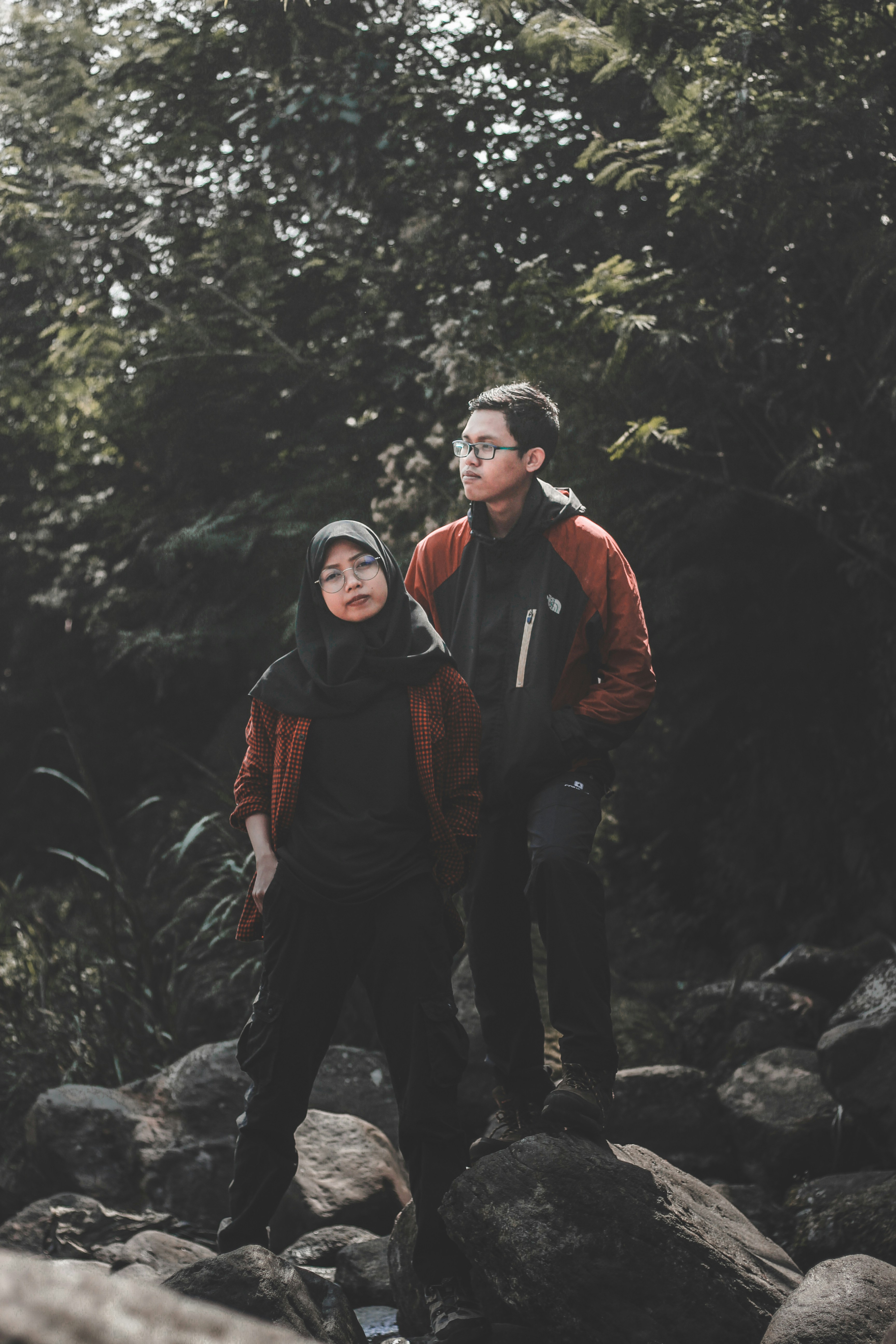 shallow focus photo woman and man standing on rock formation during daytime