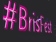Neon sign with the words '#BrisFest' glowing in bright pink against a dark background. The sign is prominent and eye-catching.