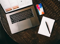 MacBook beside iPhone X on brown table
