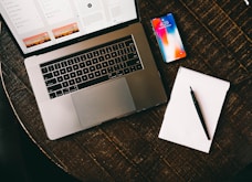 MacBook beside iPhone X on brown table