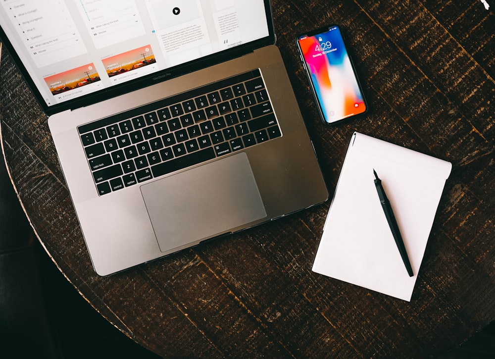 MacBook beside iPhone X on brown table