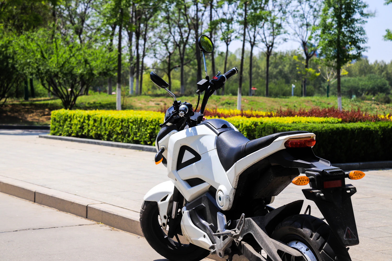 Small white 125 cc naked motorcycle parked on a garden path