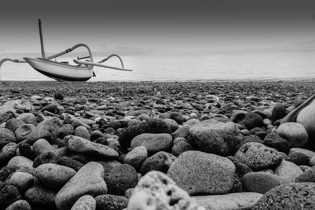 grayscale photo of white boat on beach