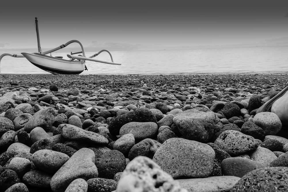 grayscale photo of white boat on beach
