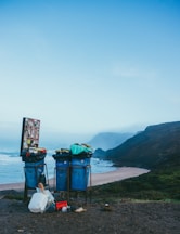 3 blue garbage cans in beach