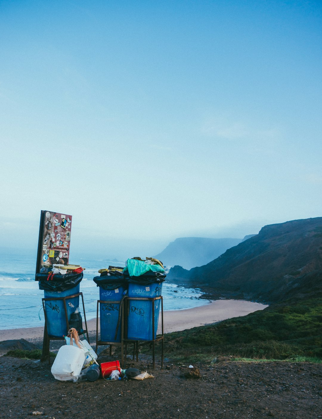  3 blue garbage cans in beach dustbin