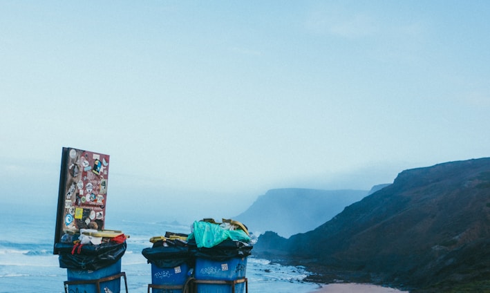 3 blue garbage cans in beach