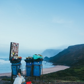 3 blue garbage cans in beach