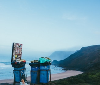 3 blue garbage cans in beach