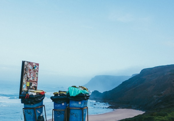 3 blue garbage cans in beach