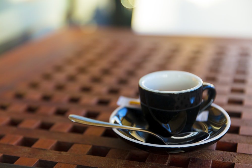 black ceramic cup and saucer with teaspoon on table