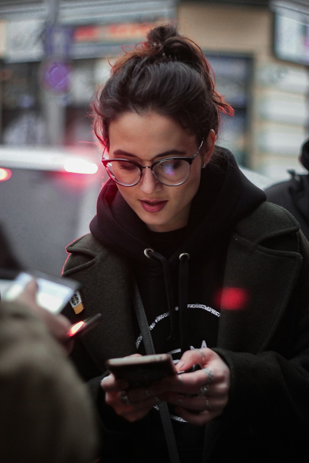 woman in black coat with smartphone on hands