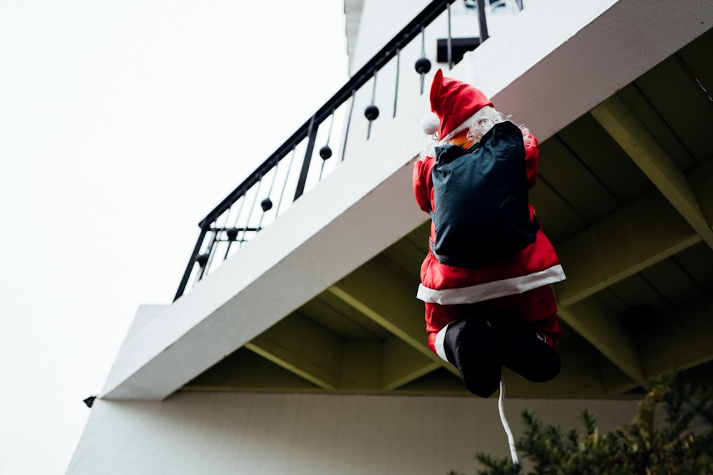 person in red jacket holding the white rope attached to black metal balcony fence