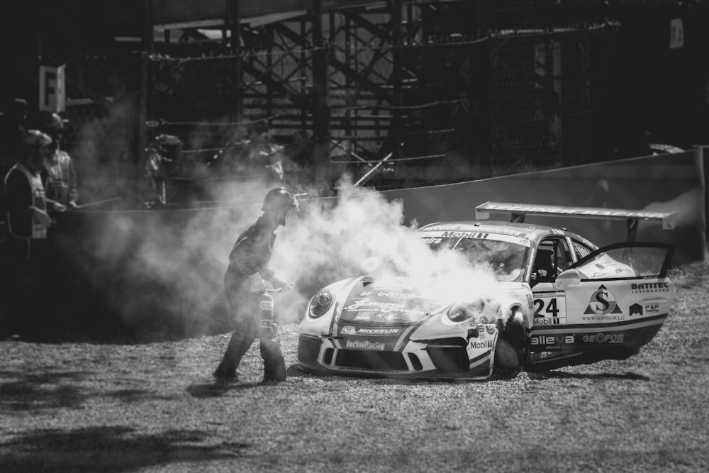 person standing in front of parked smoking race car