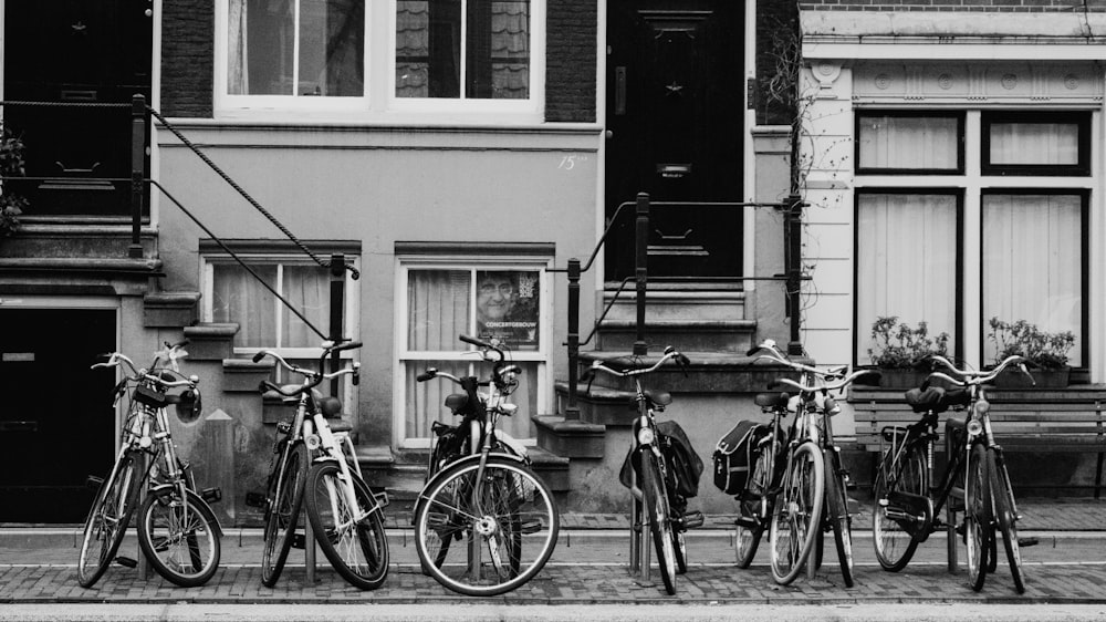 grayscale photo of bikes parked near house