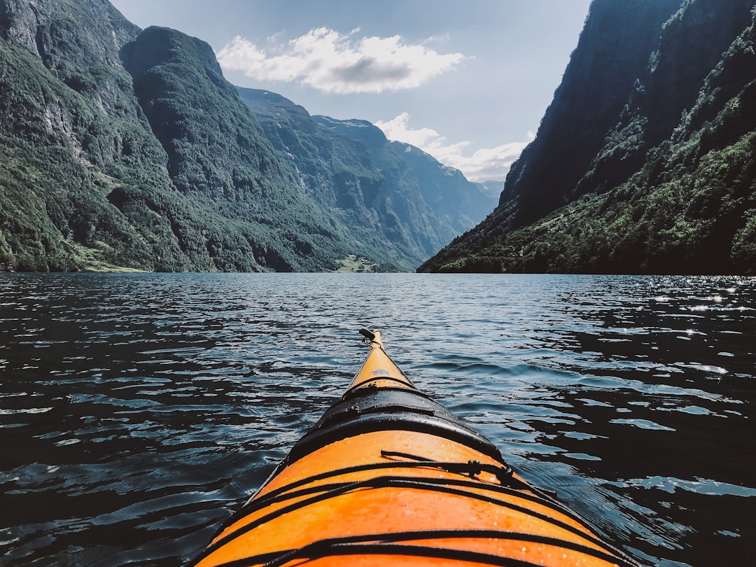 person in orange kayak in lake surrounded by hills