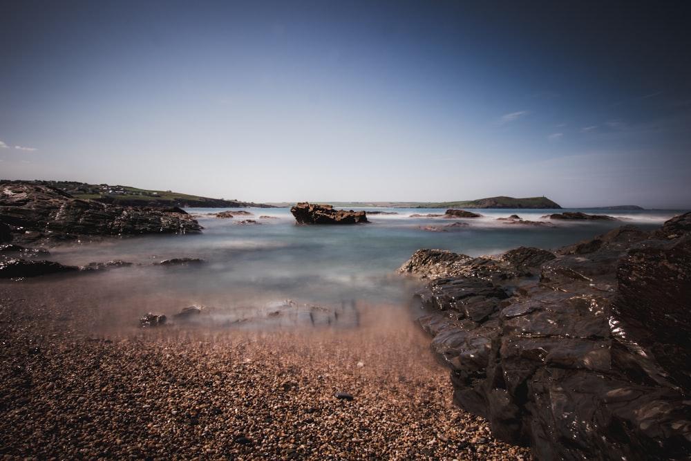 clear sky over brown sand beach with rocks