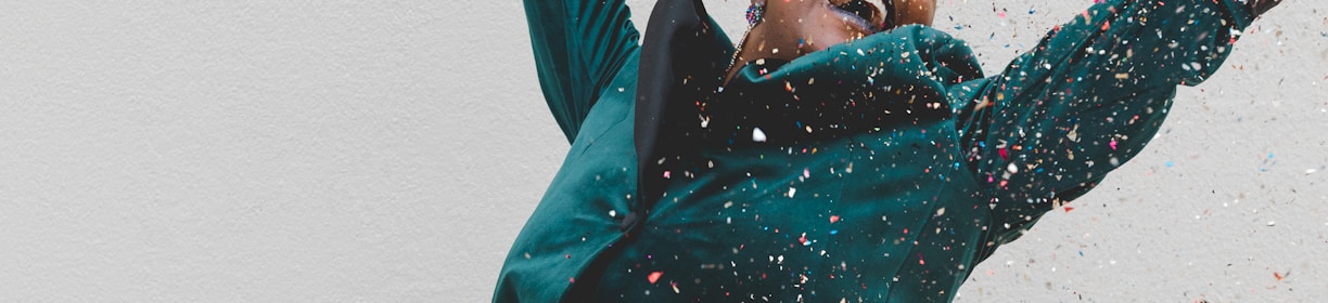 woman in green jacket raising her hands