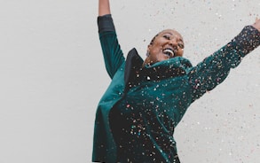 woman in green jacket raising her hands