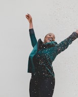 woman in green jacket raising her hands