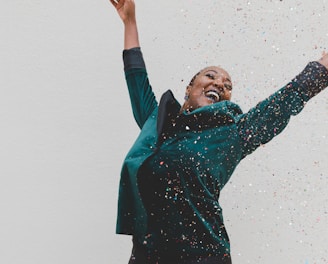 woman in green jacket raising her hands