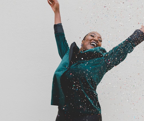 woman in green jacket raising her hands