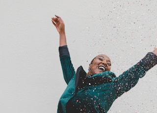 woman in green jacket raising her hands