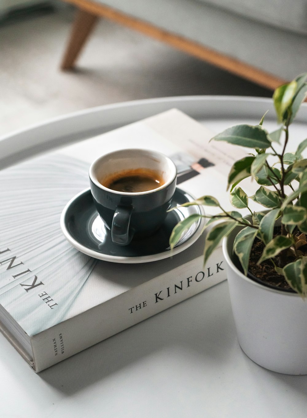 shallow focus photo of black ceramic mug and saucer on white book