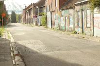 An empty, neglected urban sewer grate with graffiti nearby, representing forgotten spaces.