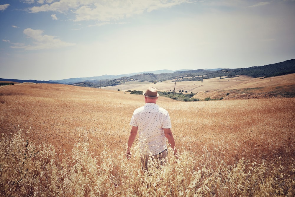 man standing between brown field