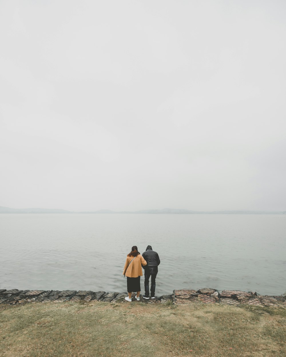 two person standing in front of body of water during daytime