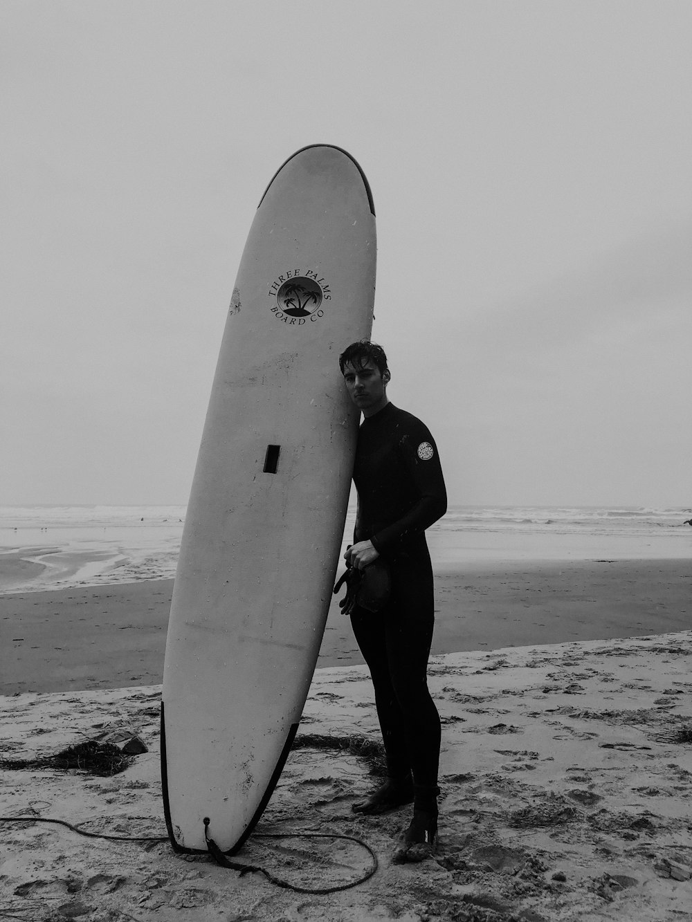 Homem segurando prancha de surf branca perto da costa do mar