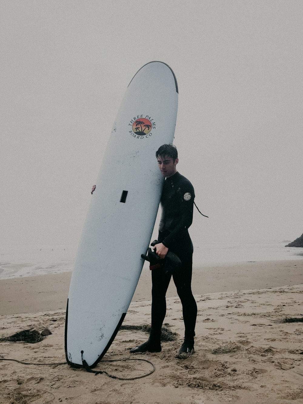 uomo in piedi sulla sabbia con tavola da surf