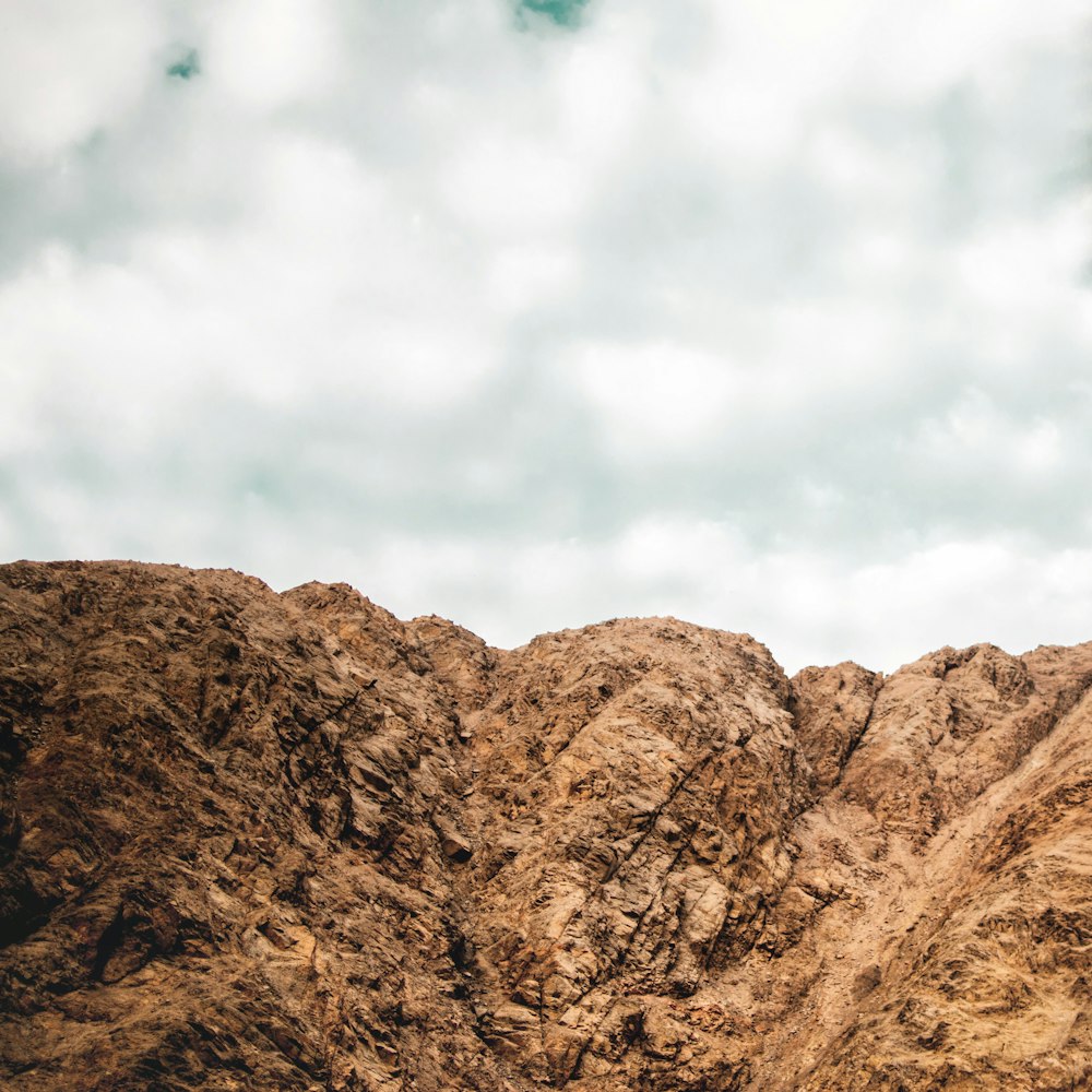 brown mountain under cloudy sky during daytime