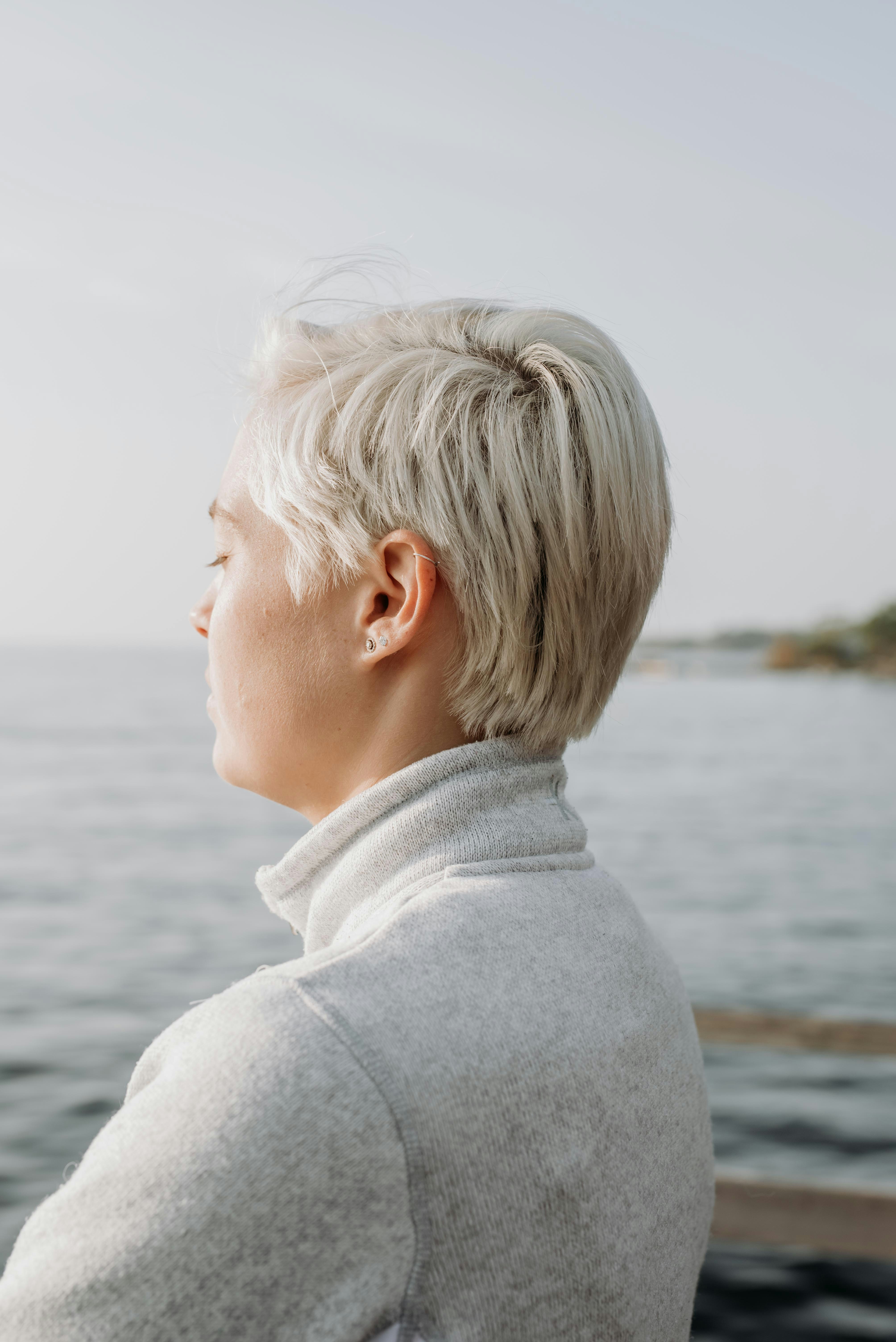woman with blonde hair wearing gray sweater at dock