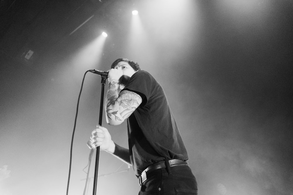 grayscale photography of man holding microphone