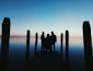 silhouette of three person on seadock