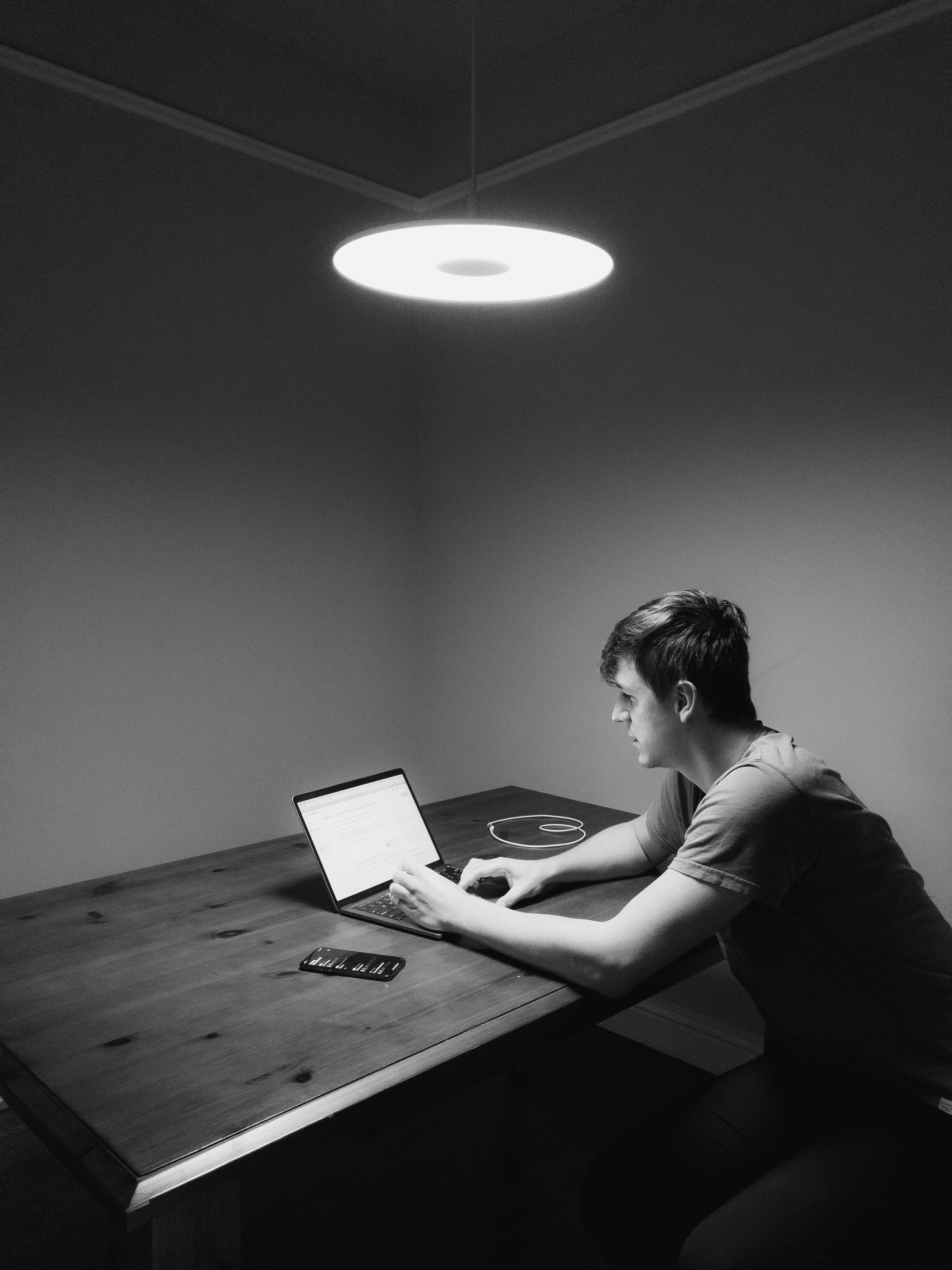 grayscale photography of man siting facing laptop computer