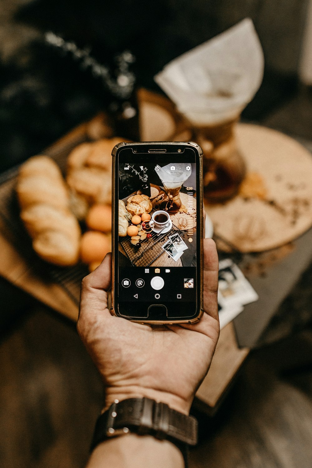 person capturing breads and coffee on smartphone