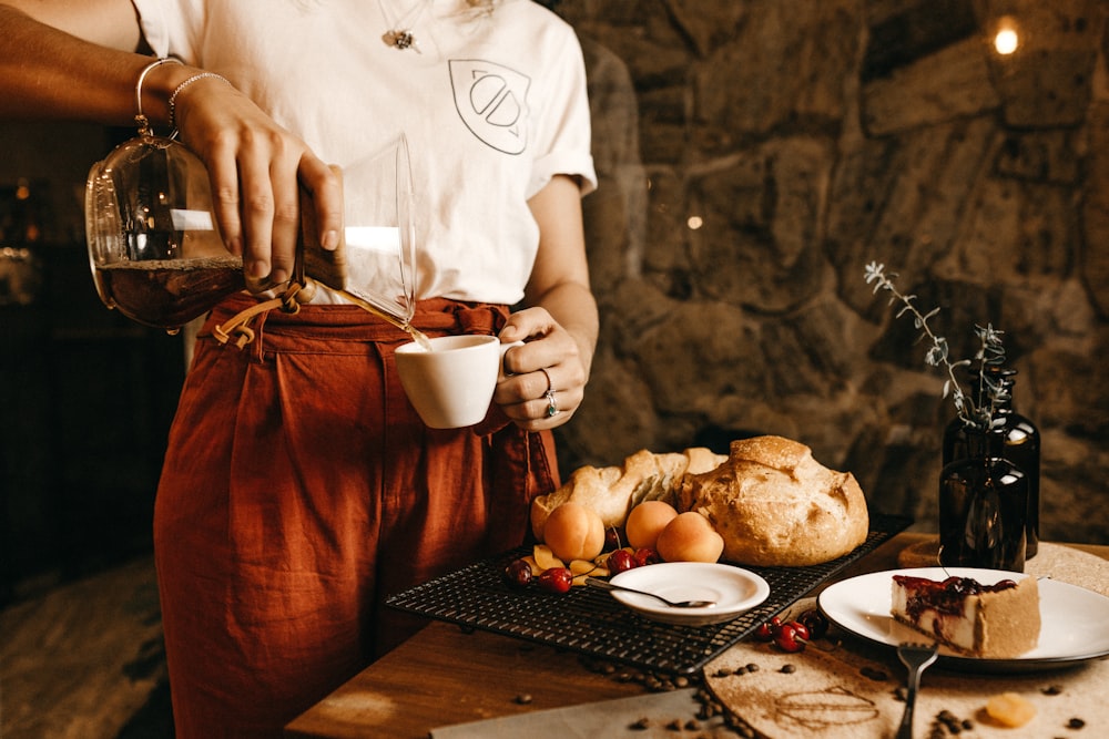 person pouring brown liquid on tea cup