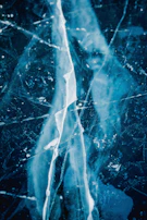 Close-up texture of cracked ice revealing deep blue hues.