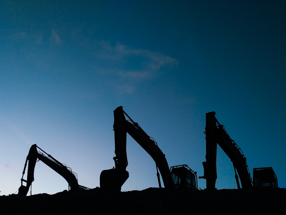 three excavators during day