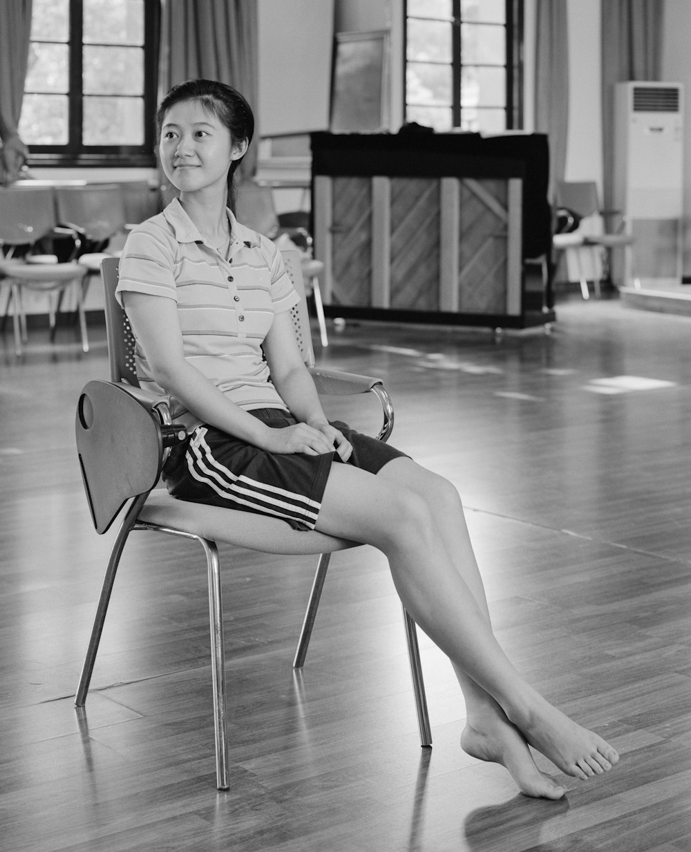 grayscale photography of woman sitting on chair inside house