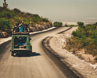 A family happily driving an electric SUV through a green countryside road.