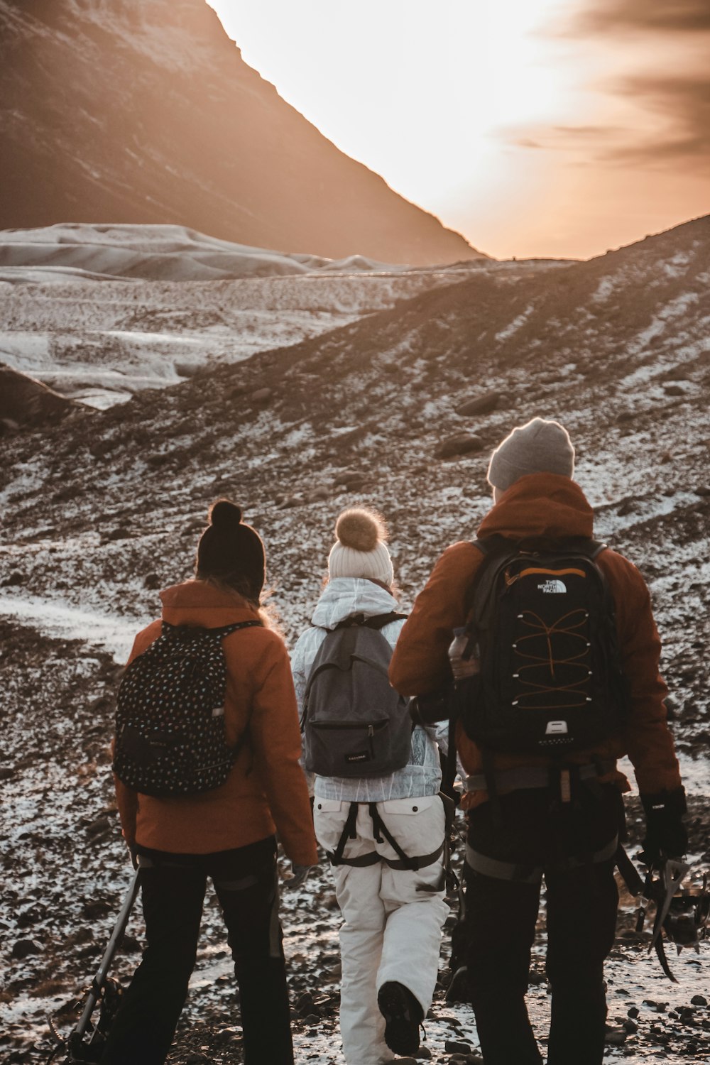 three people walking beside mountain