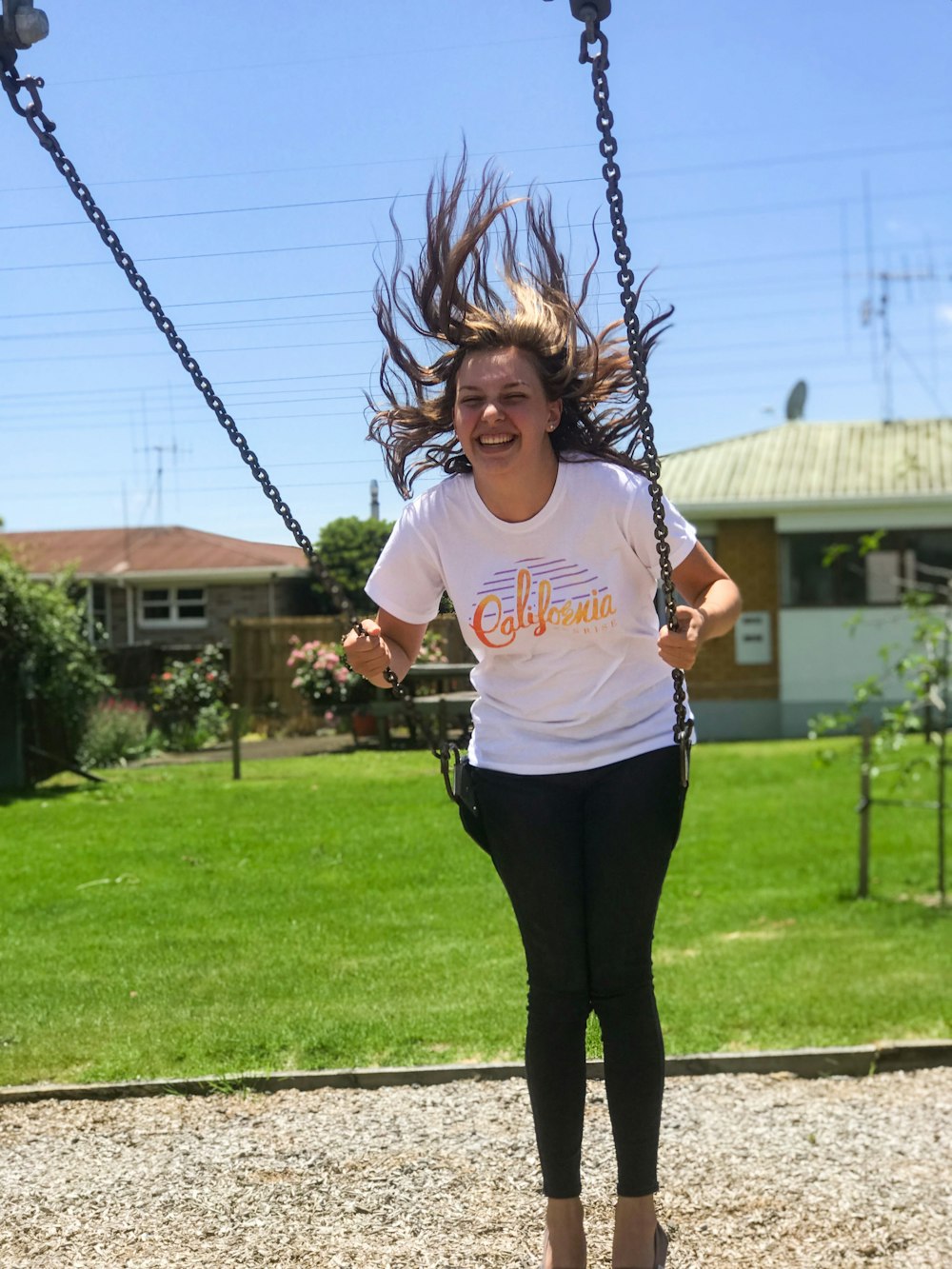 woman in white shirt and black leggings riding swing at park